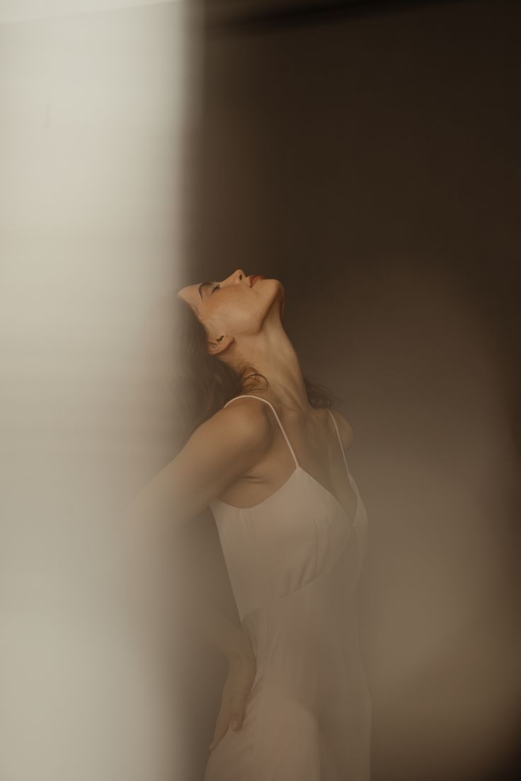 A woman leaning back, eyes closed, in soft light
